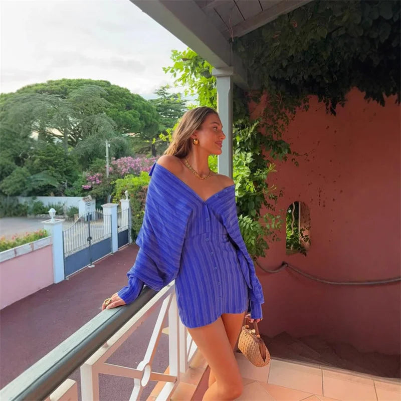 Woman in a blue outfit standing on a balcony with greenery in the background