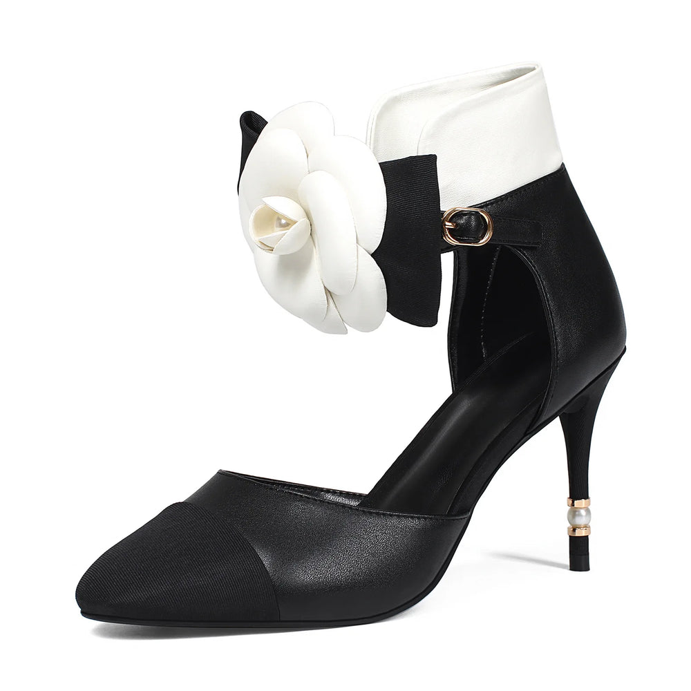 Black high-heeled shoe with a white flower accessory on a white background