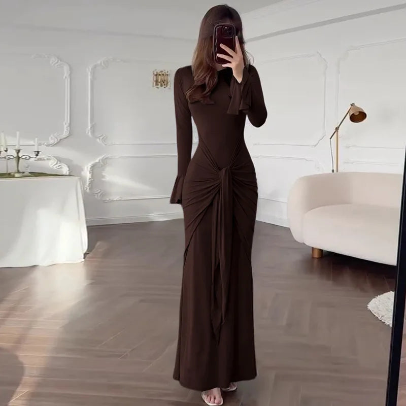 Woman taking a mirror selfie wearing a brown long-sleeve dress in a modern room.