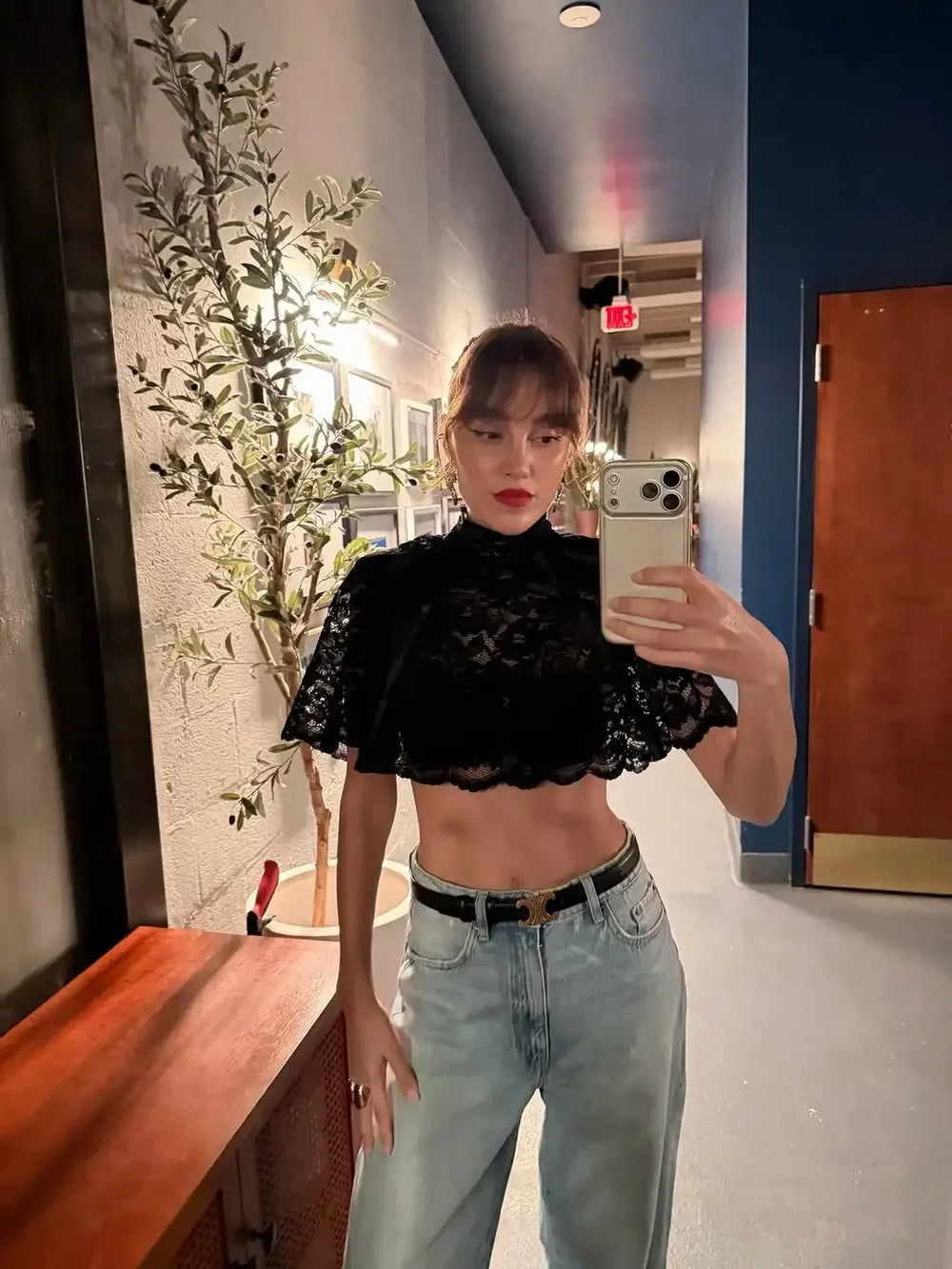 Person taking a mirror selfie wearing a black lace top and light blue jeans.