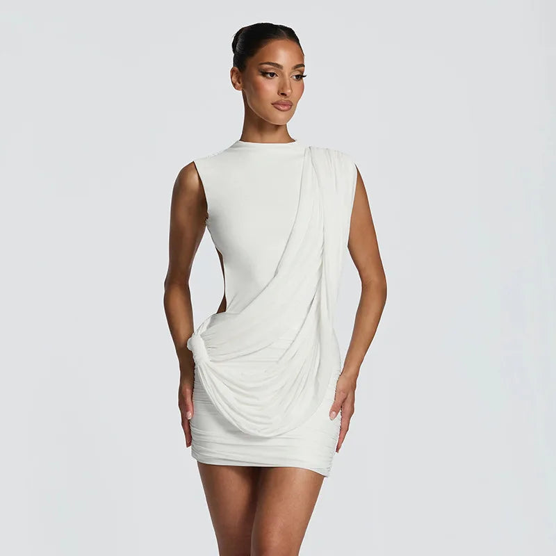 Woman wearing a white draped dress against a plain background