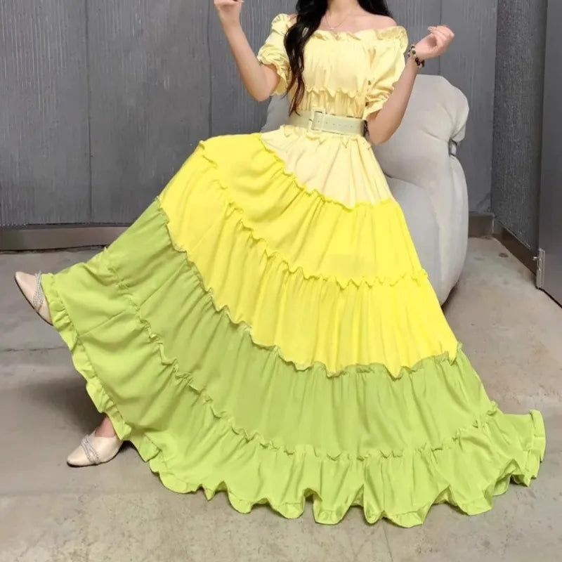 Woman wearing a yellow and green dress with ruffled layers in a room.