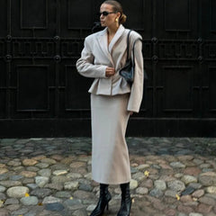 Woman in a stylish outfit standing on a cobblestone street.