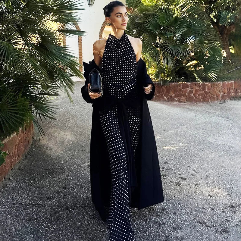 Woman in a black and white patterned outfit standing outdoors with greenery in the background