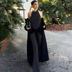 Woman in a black and white patterned outfit standing outdoors with greenery in the background