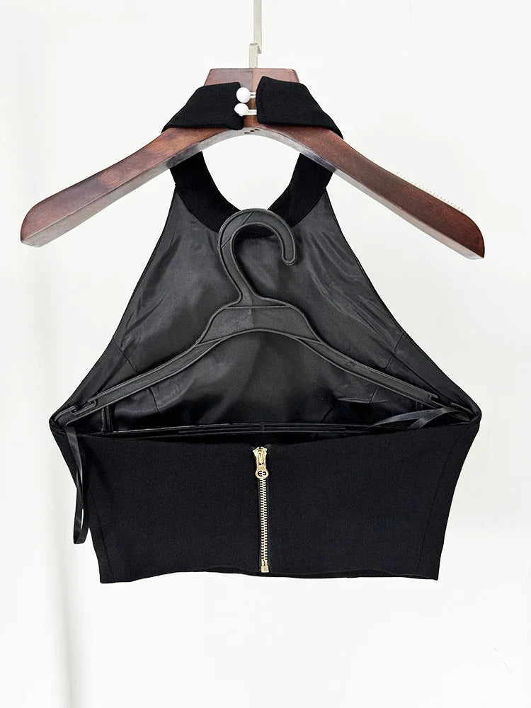 Black halter top with a zipper on a wooden hanger against a white background