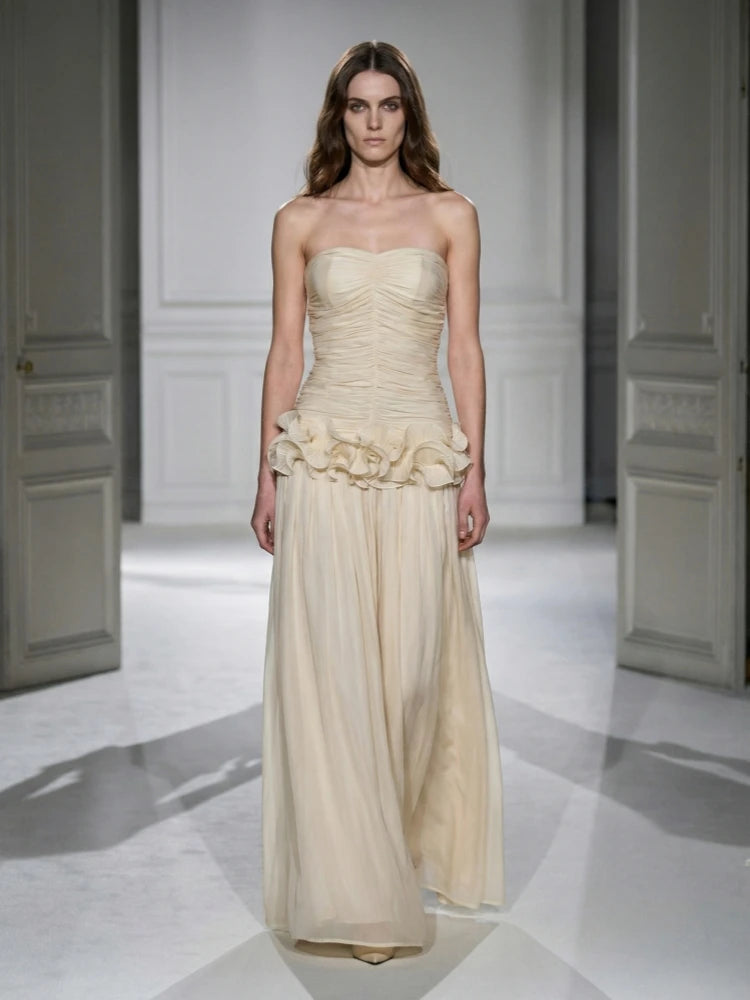 Woman wearing a strapless, ruffled gown on a white runway