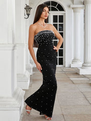 Woman wearing a black strapless dress with white embellishments in front of a classical building.