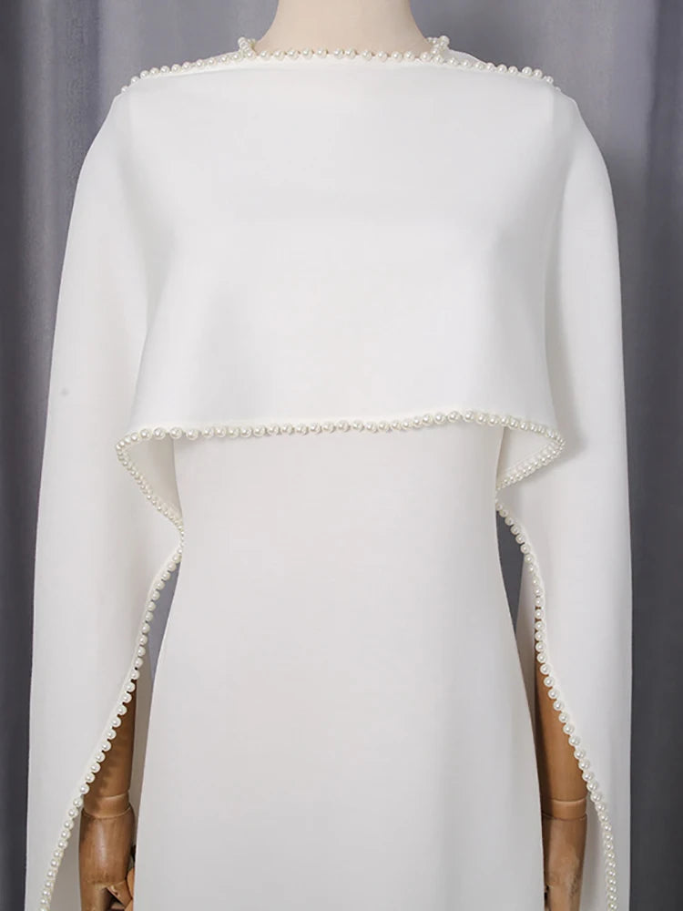 White cape with pearl trim on a mannequin against a gray background