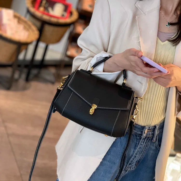 Person holding a black handbag and a phone in an indoor setting