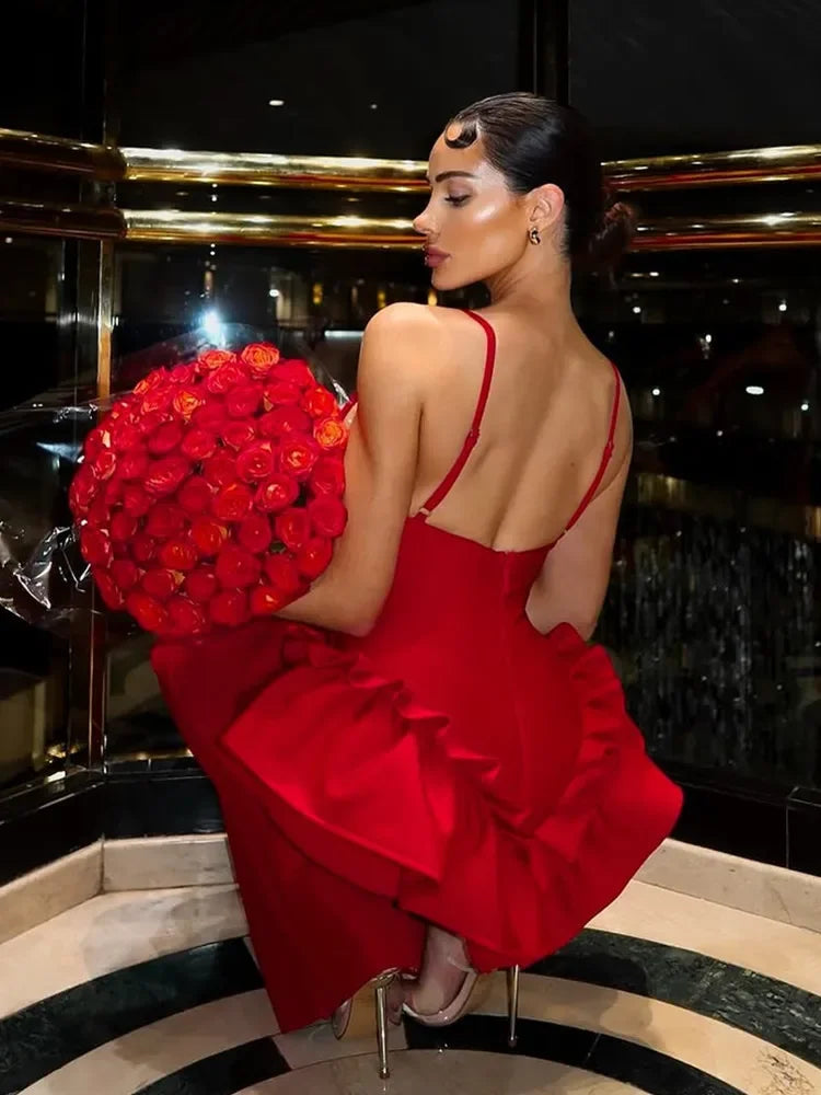 Woman in a red dress holding a large bouquet of red roses in an elegant interior setting.