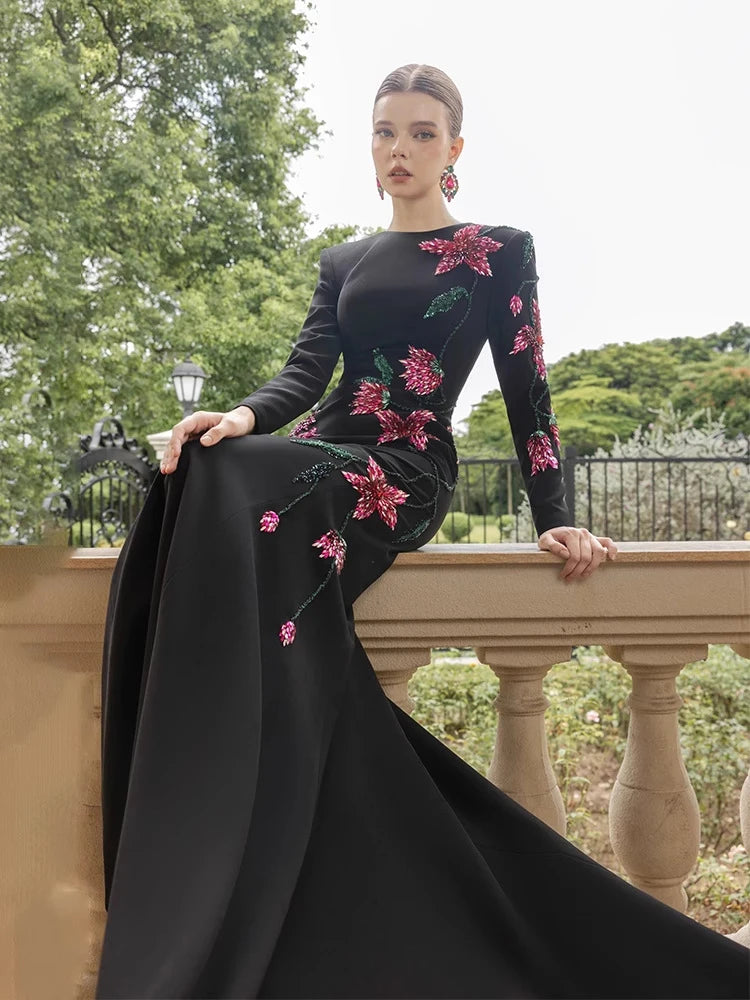 Woman sitting in black long sleeve gown with floral beading
