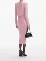 Person wearing a pink outfit holding a black handbag on a white background