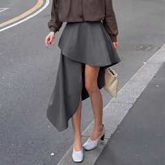 Close-up of the fabric and asymmetrical hem of a high-waisted skirt.