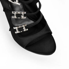 Close-up of the buckle detailing on black satin multi-strap stiletto sandals
