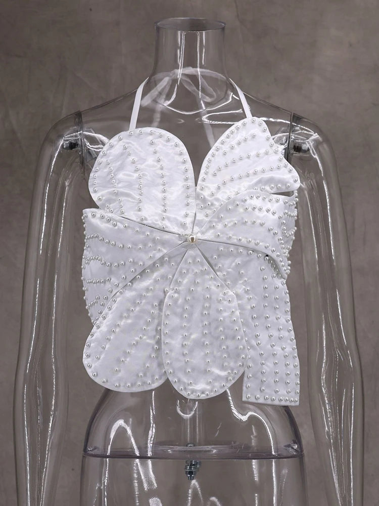 White butterfly-shaped garment on a mannequin against a gray background