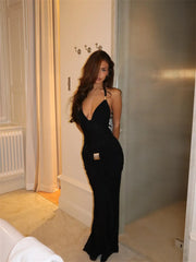 Woman in a black dress standing in a room with neutral decor.