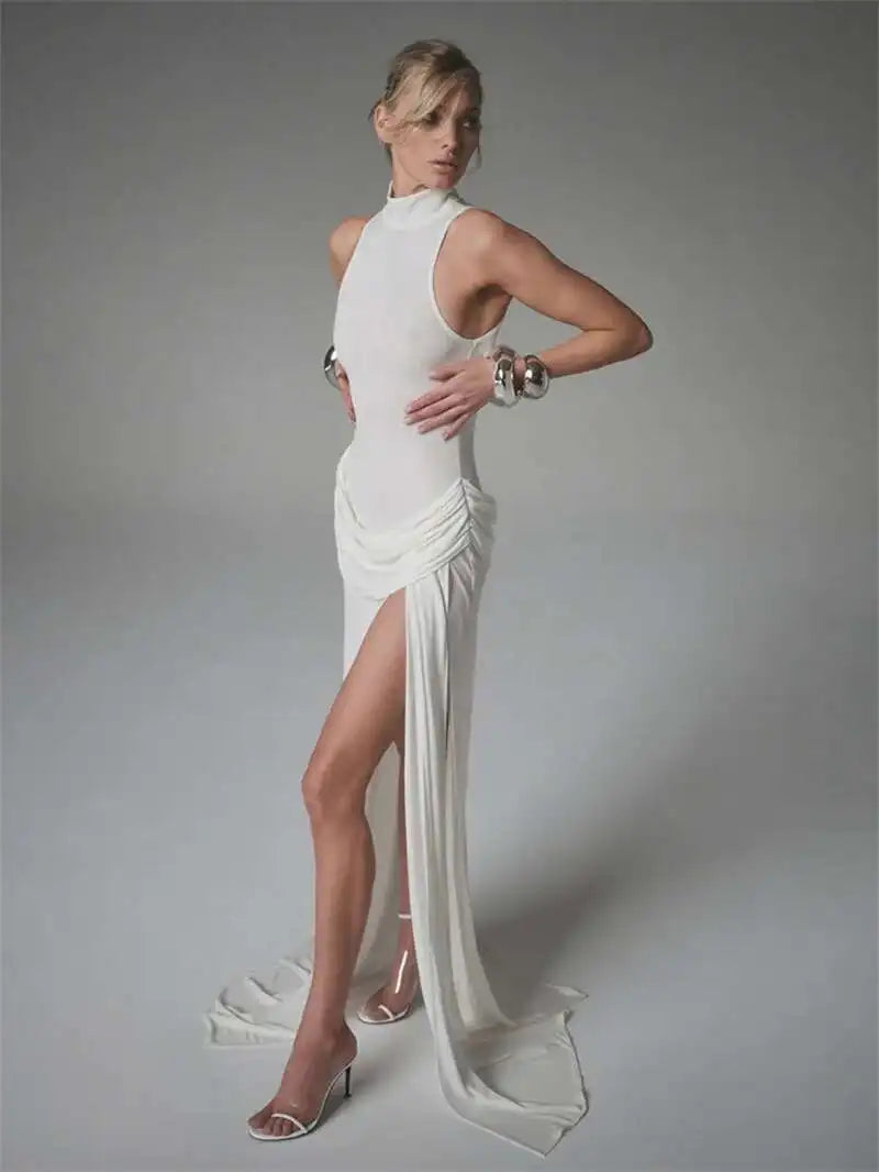 Woman wearing a white evening gown with a high slit on a gray background
