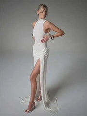 Woman wearing a white evening gown with a high slit on a gray background