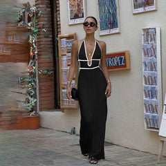 Woman in a black and white dress standing in front of a wall with posters and a 'Tropes' sign.