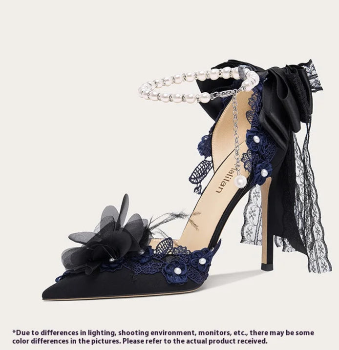 Navy blue high-heeled shoe with floral and lace details on a light gray background