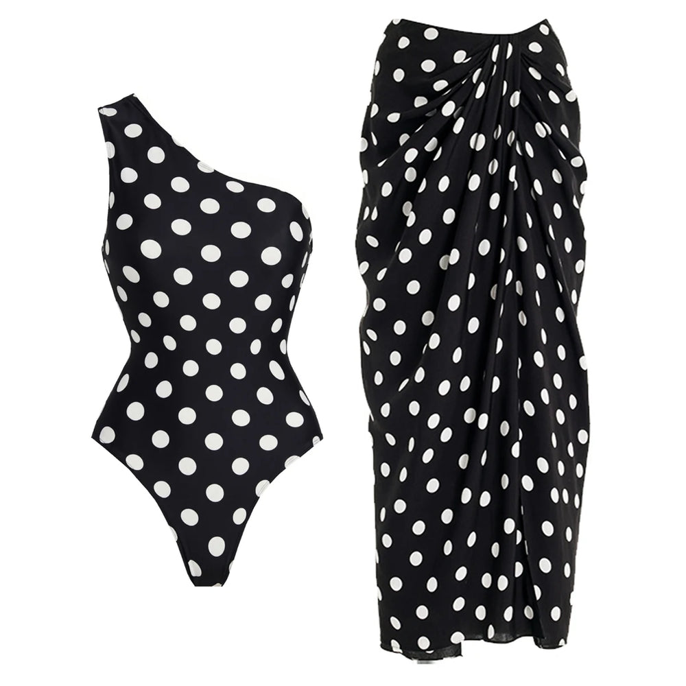 Black and white polka dot one-shoulder one-piece swimsuit with a matching draped sarong