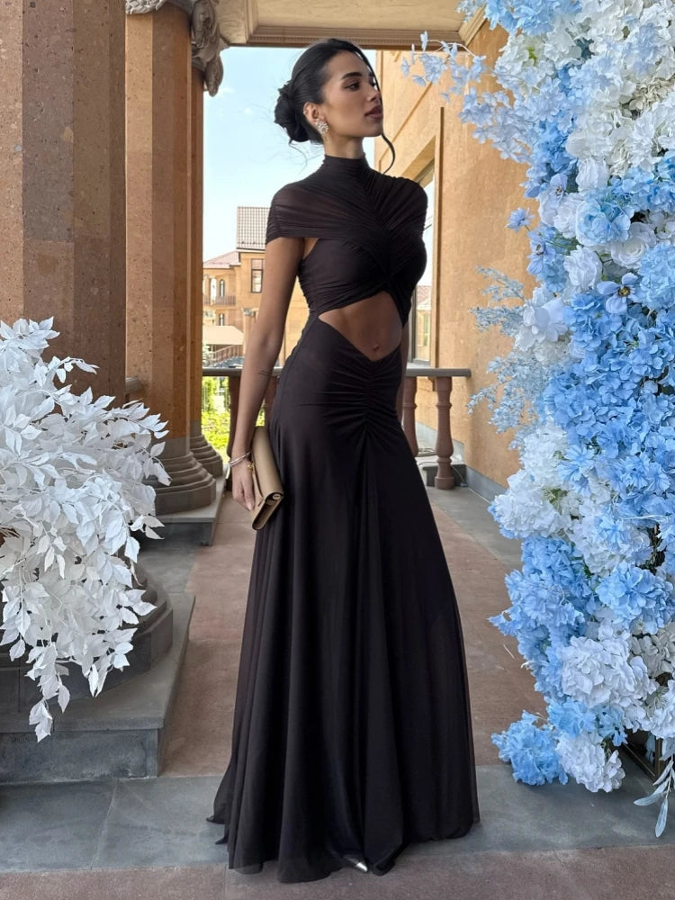 Woman in a black evening gown standing between floral decorations