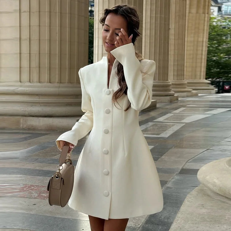 Woman in a white coat standing in front of classical architecture