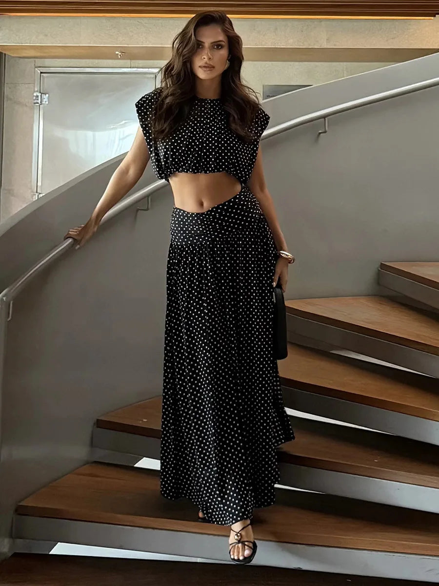 Black polka dot sleeveless crop top and flowing maxi skirt on a woman standing on stairs