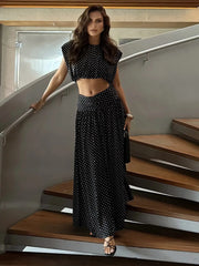 Black polka dot sleeveless crop top and flowing maxi skirt on a woman standing on stairs