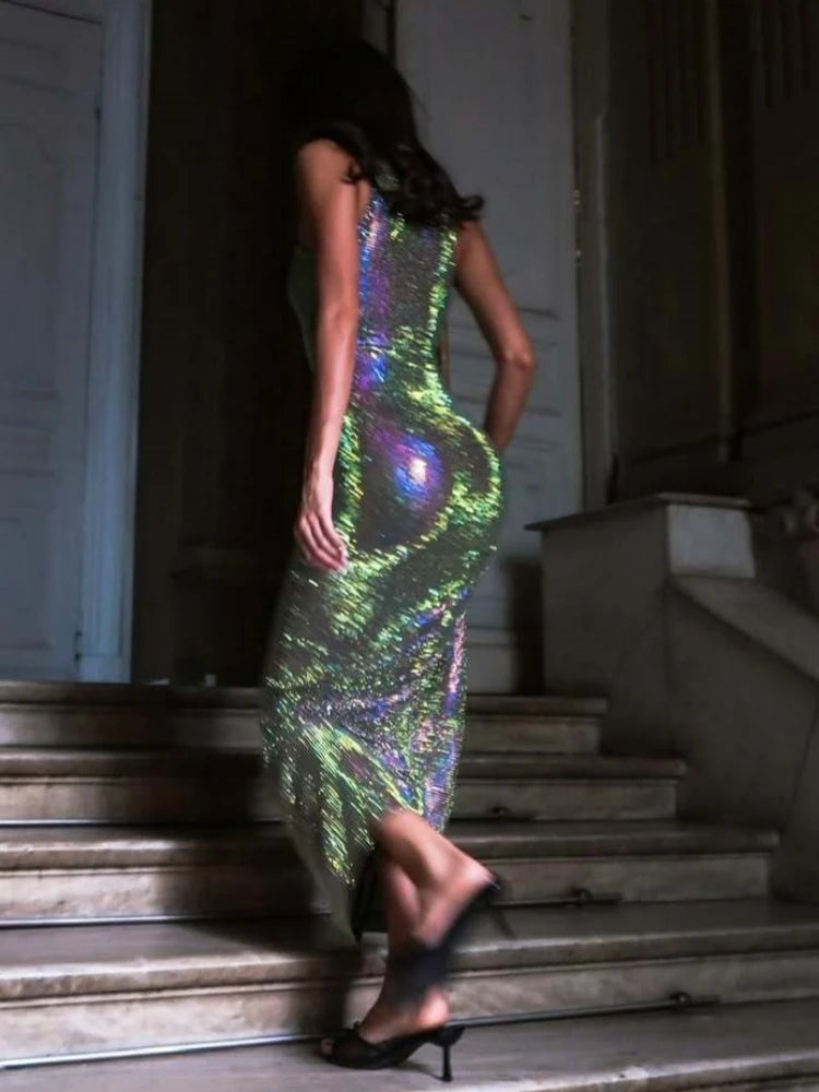 Woman in a colorful, reflective dress standing on steps indoors