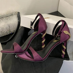 Purple high-heeled shoes with gold accents on a black surface.