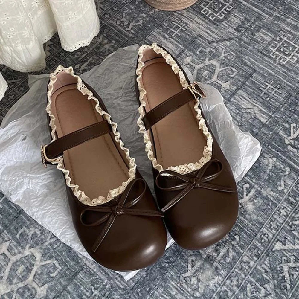 Brown lace ruffled bow Mary Jane flats on textured surface