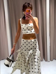 Person wearing a polka dot outfit with a white curtain background