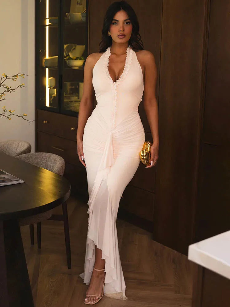 Woman in a white halter neck dress standing in an indoor setting.