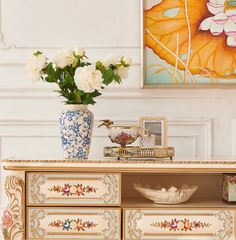Decorative cabinet with floral arrangement and artwork in a room setting