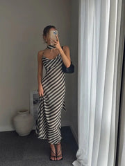 Person wearing a black and white striped dress in a room with a vase and framed picture on the wall.