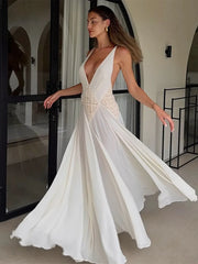 Woman wearing a white evening gown with a deep neckline in an indoor setting.