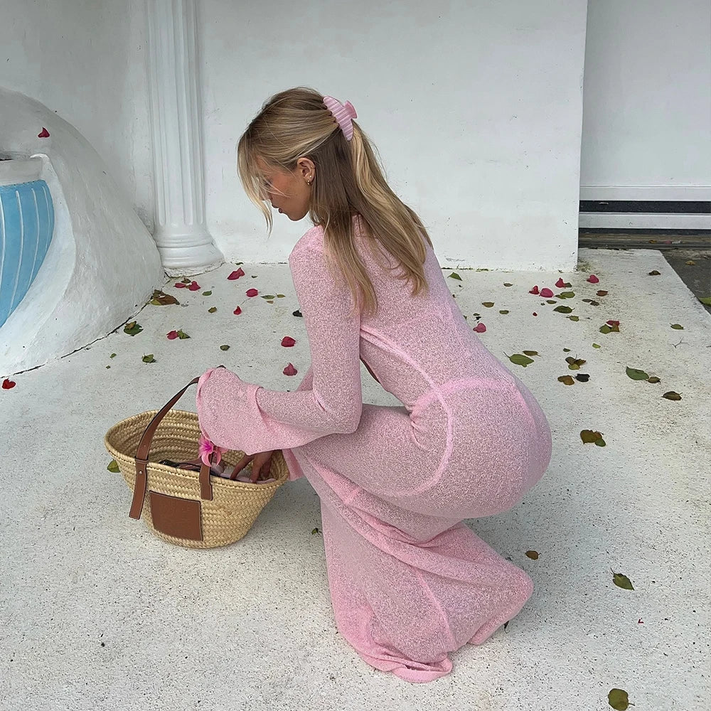 Model crouching with a woven basket wearing a ribbed knit long sleeve cover-up and bikini bathing suit set.