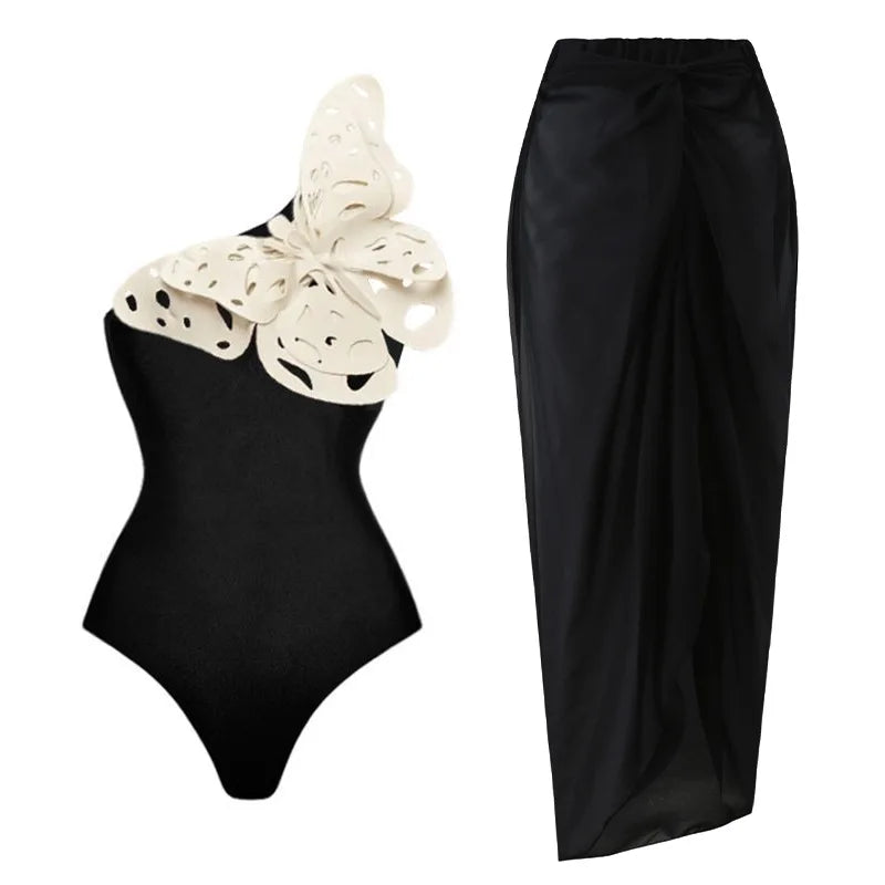 Black one-piece swimsuit with a white perforated butterfly detail and a black ruched maxi skirt.