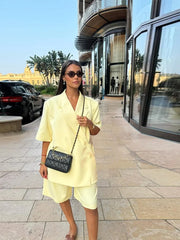 Woman in a yellow outfit walking on a sidewalk with a building in the background