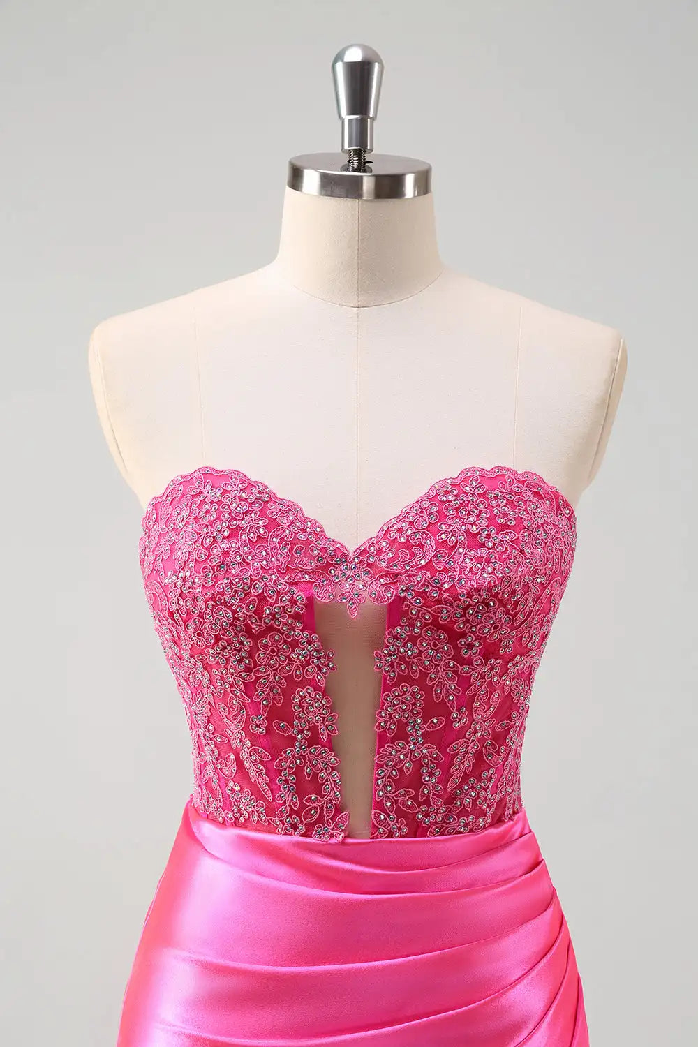 Pink beaded top and satin skirt on a mannequin against a gray background