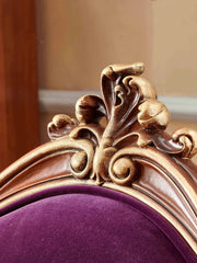 Decorative gold frame with intricate designs on a purple cushion