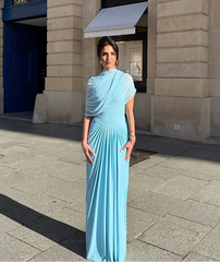 Woman in a light blue dress standing on a street with a building in the background