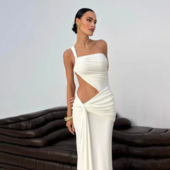Woman in a white one-shoulder dress standing against a plain background