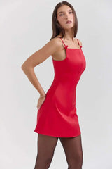 Woman wearing a red slip dress on a white background