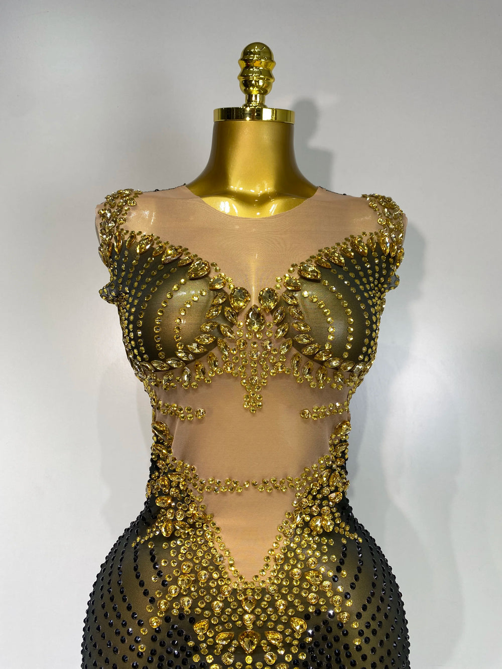 Gold beaded dress on a mannequin against a white background