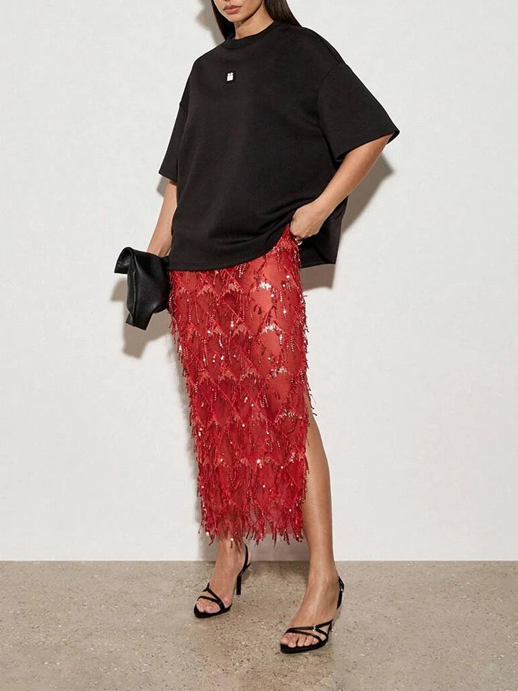 Person wearing a black oversized top and red sequin skirt with a white background