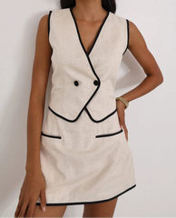 Woman wearing a beige dress with black trim on a white background