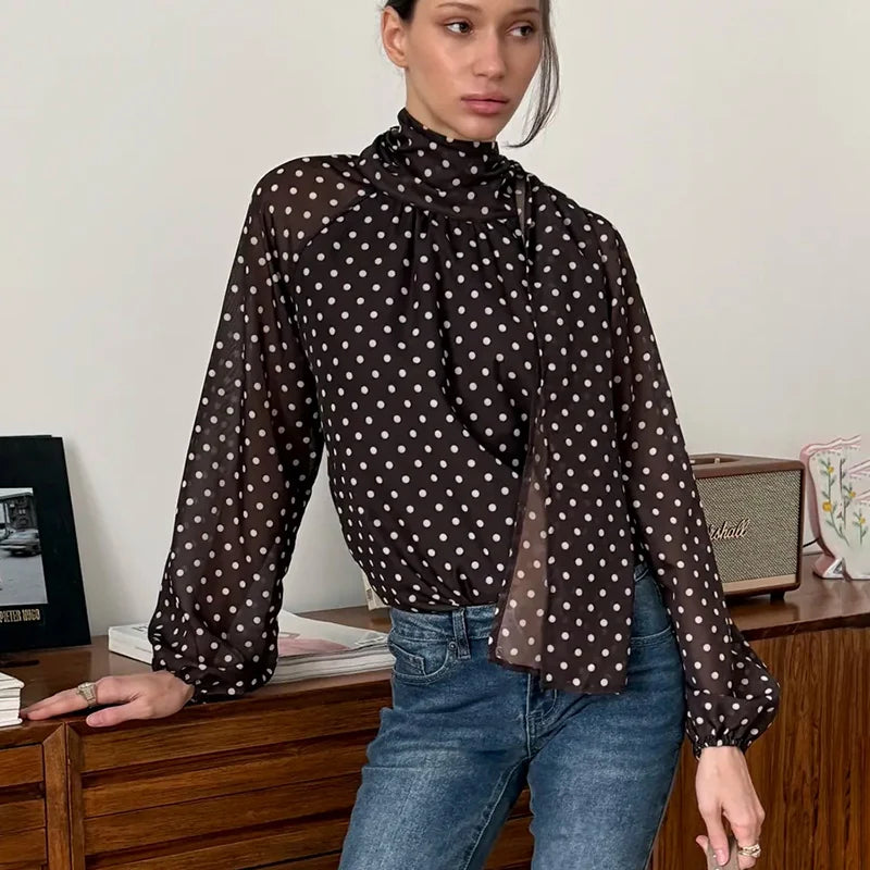 Woman wearing a polka dot blouse and blue jeans in an indoor setting.